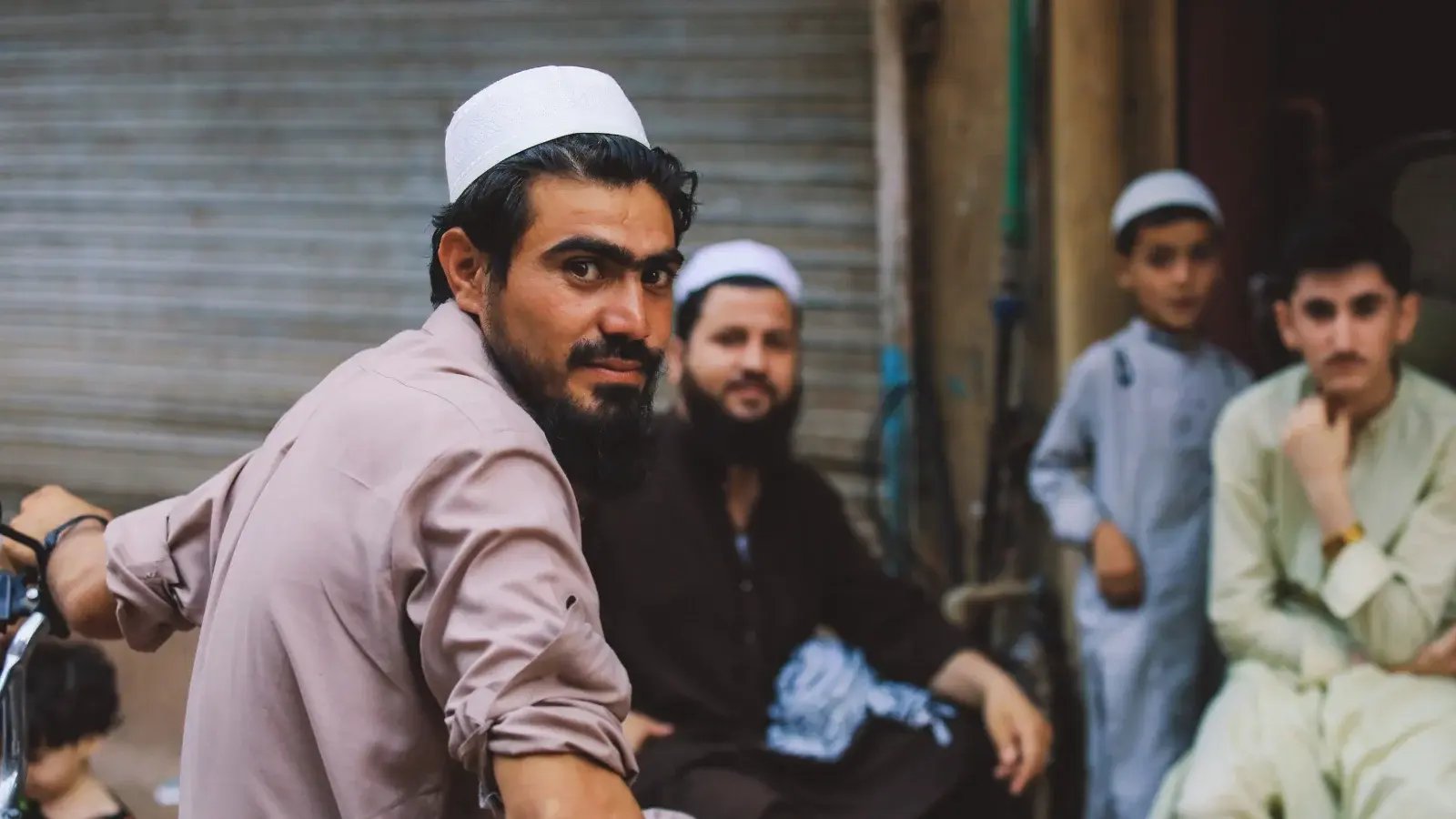 Hombres sentados frente a una tienda en Pakistán